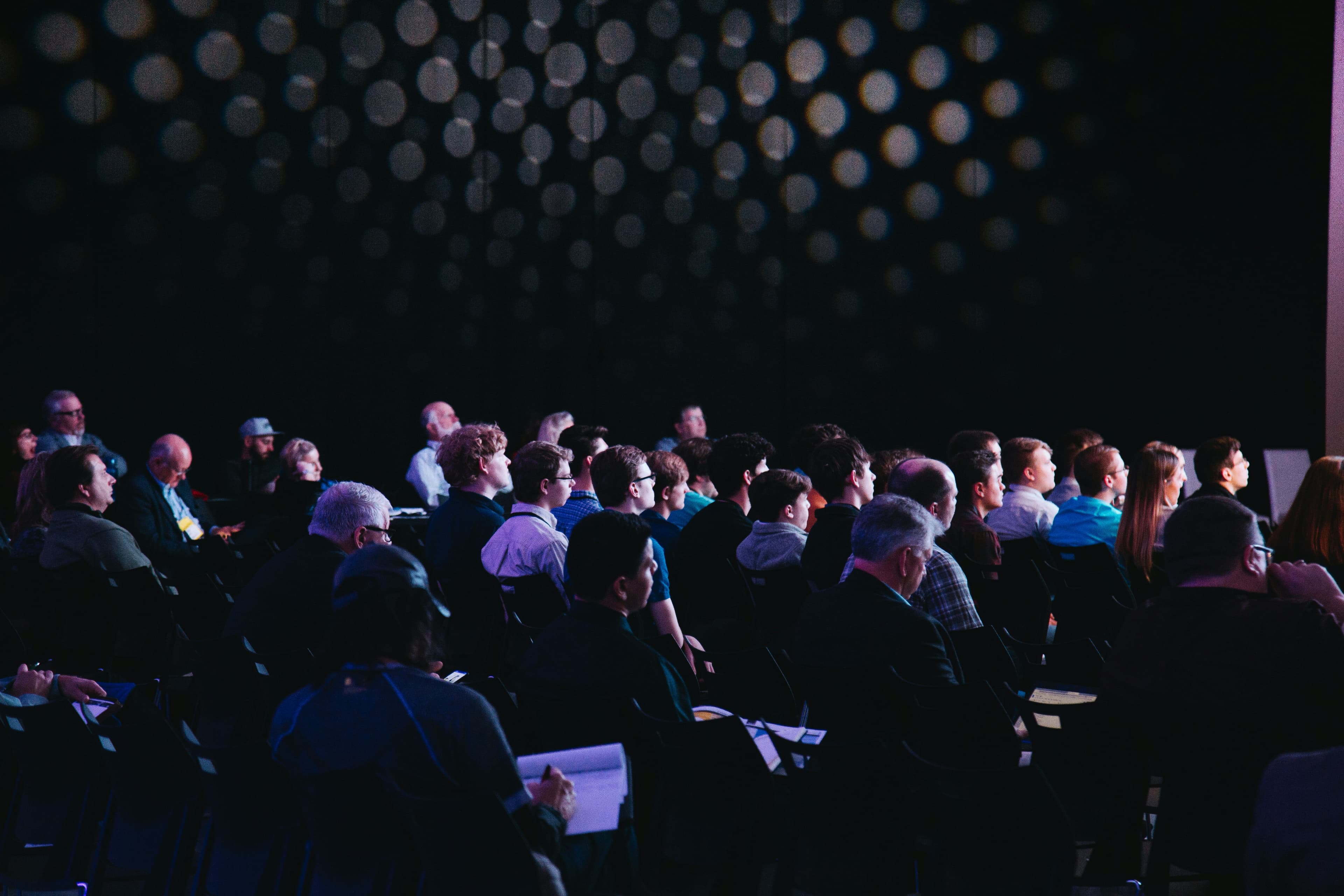 Crowd of professionals watching a presentation that seems tech or future related